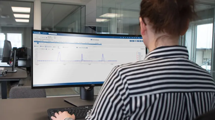 Person monitoring real-time temperature data on a computer screen using a cold chain tracking dashboard in an office setting.